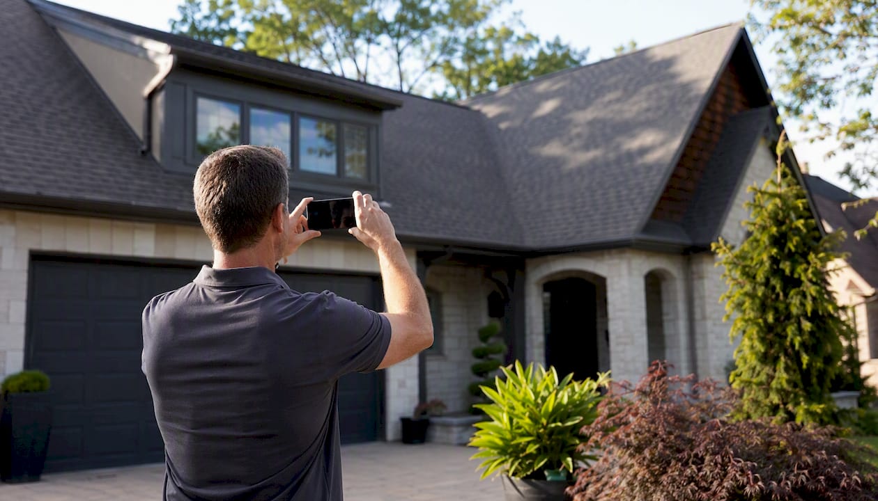 Homeowner taking photo of their roof from street