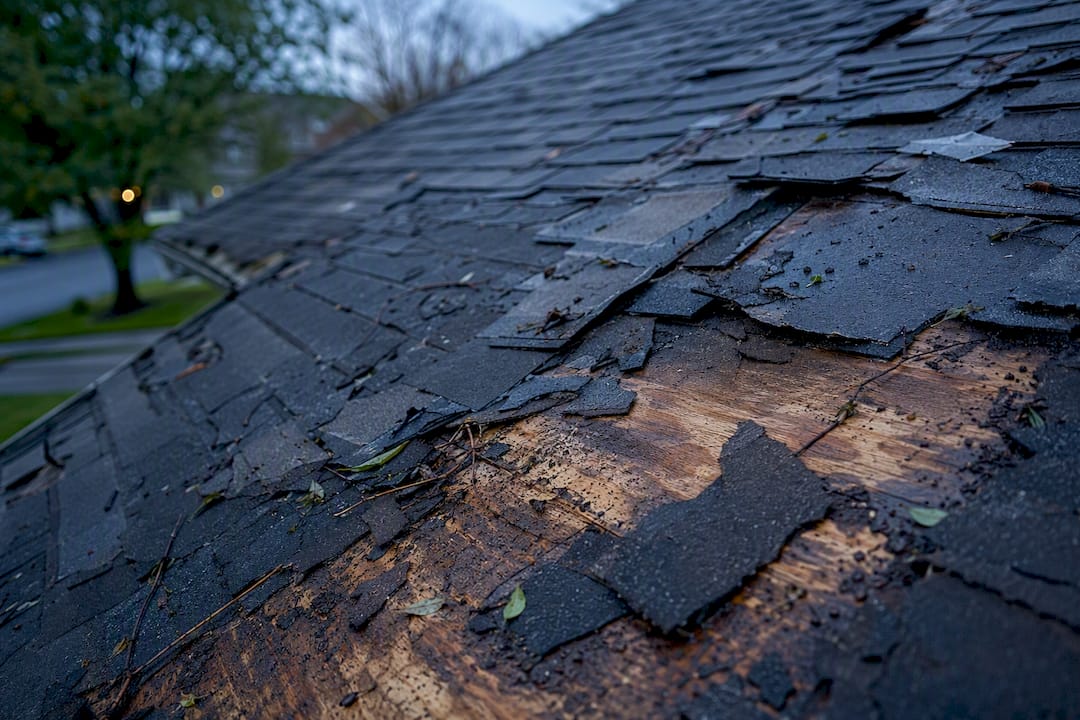 Close-up of damaged roof shingles and debris