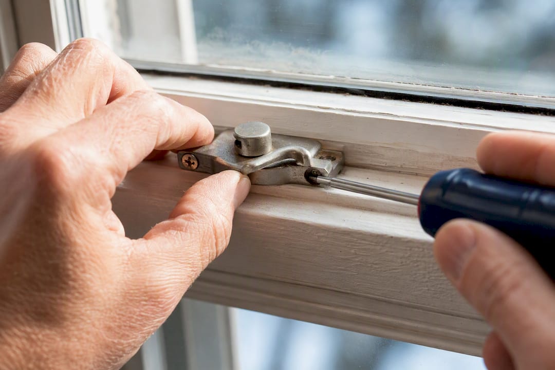 Hands checking a loose window sash lock